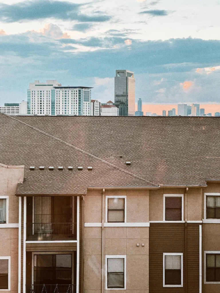 Apartment buildings with asphalt shingle roofs and a city skyline