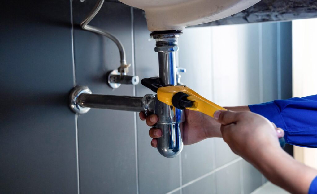 Tightening the trap under a kitchen sink during a plumbing repair