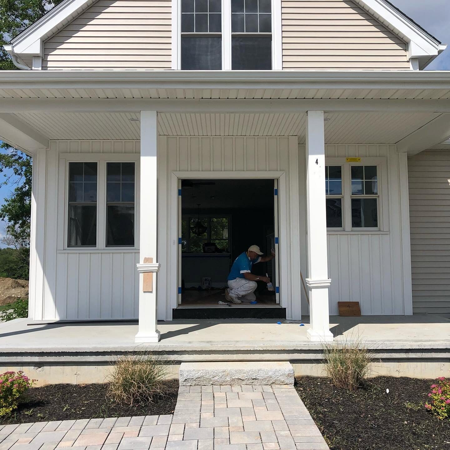 Crew painting a farmhouse front porch, columns and trim