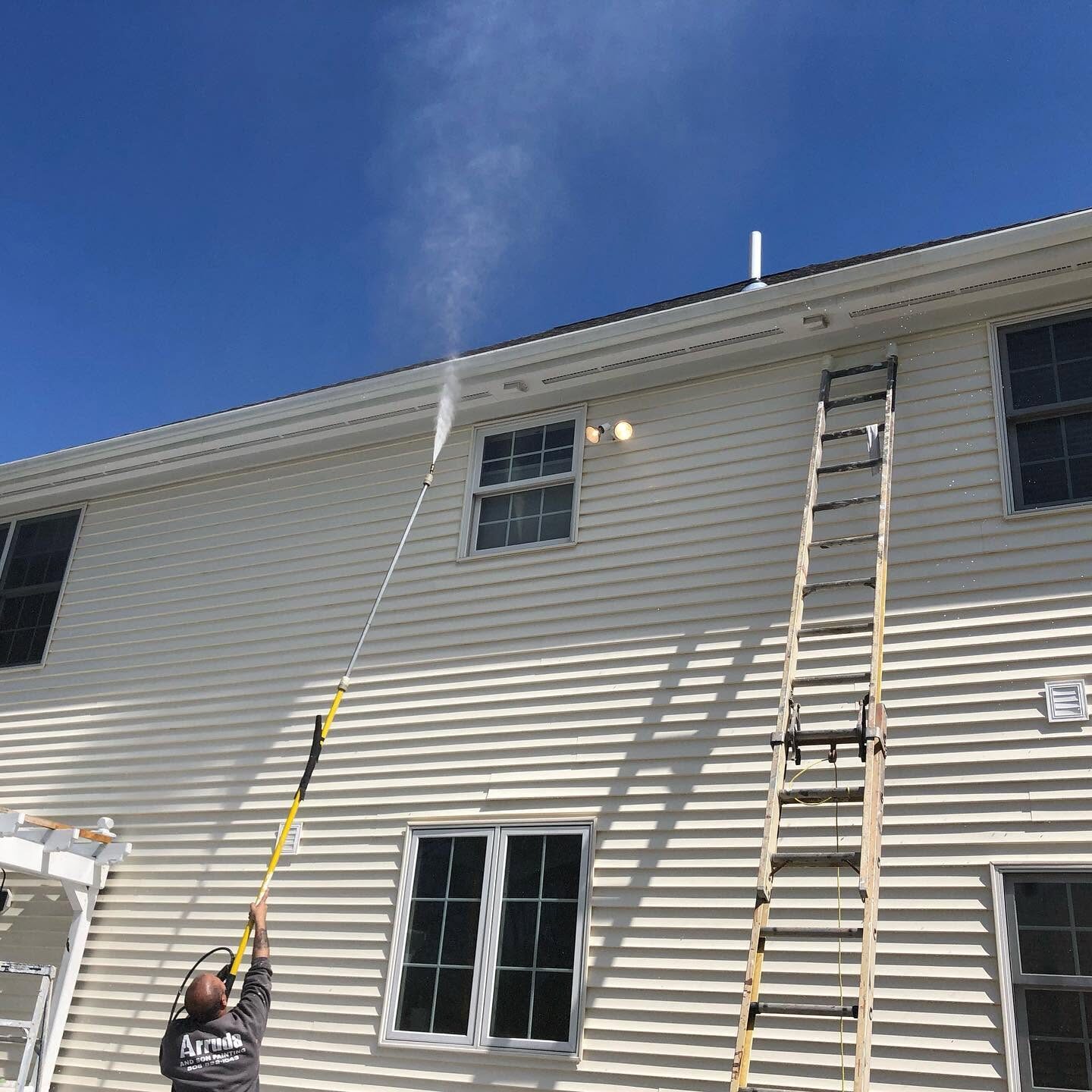 Softwashing vinyl siding on a two-story home