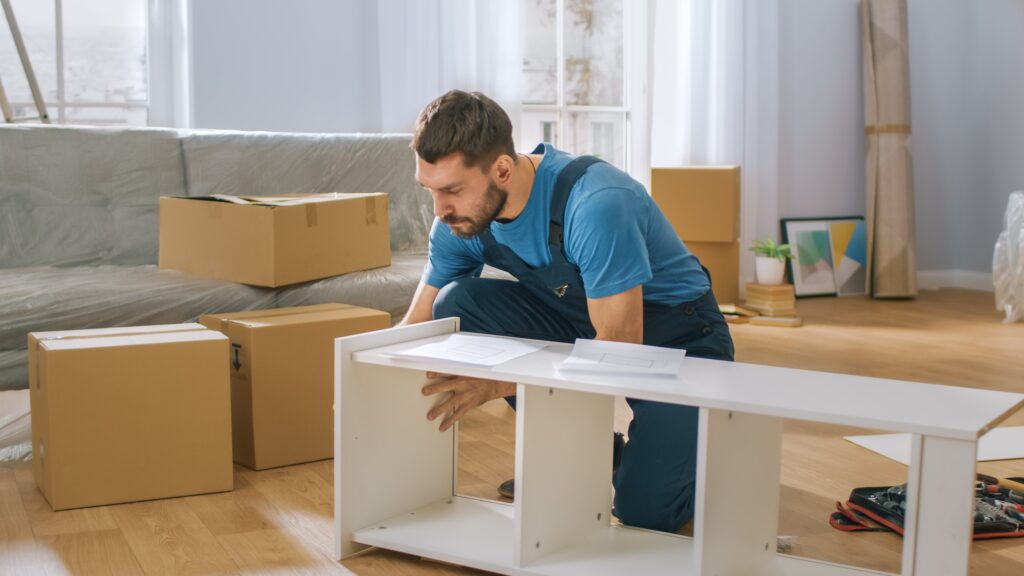 Assembling flat-pack furniture in a room still full of boxes