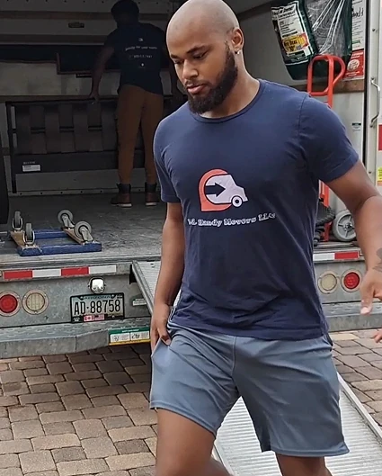 P.R. Handy Movers crew member in a branded shirt stepping off a moving trailer