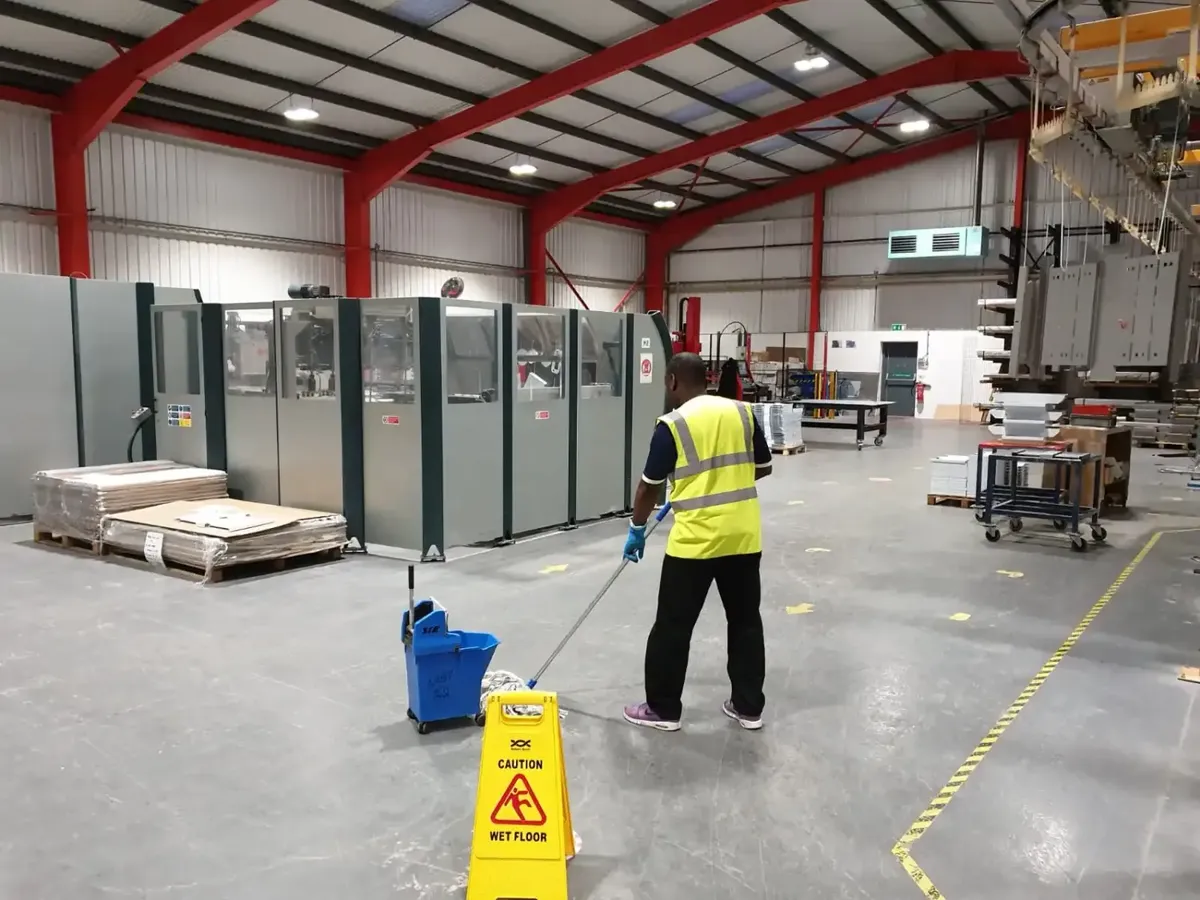 Industrial cleaning of a warehouse floor with a wet floor sign
