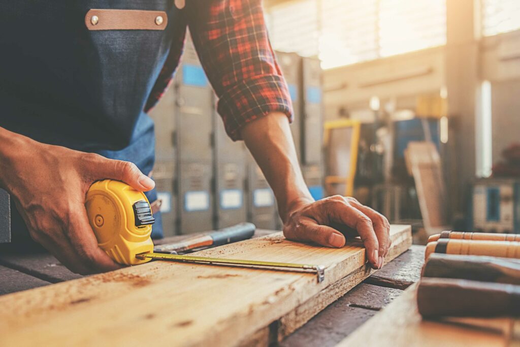 Handyman measuring a wood board with a tape measure