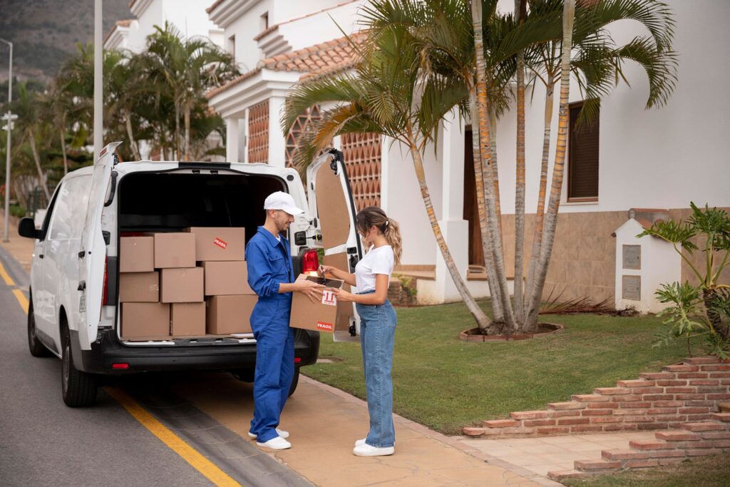 Customer handing a box to a mover beside a van full of moving boxes